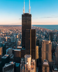 Modern buildings in city against sky during sunset