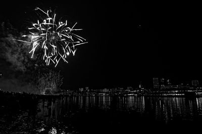 Firework display over river against sky at night