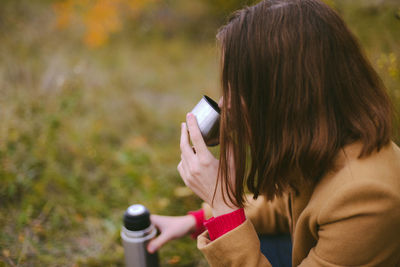 Close-up of woman drinking tea on field