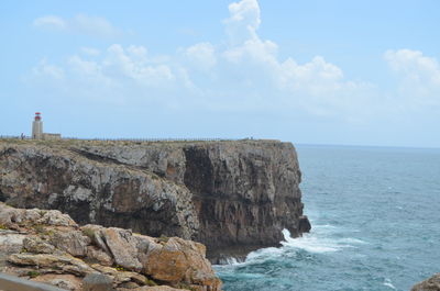 Scenic view of cliff by sea against sky