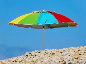 Close-up of umbrella on beach against clear blue sky