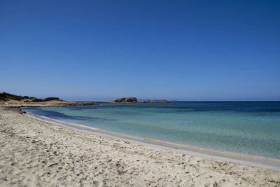 Scenic view of beach against clear blue sky