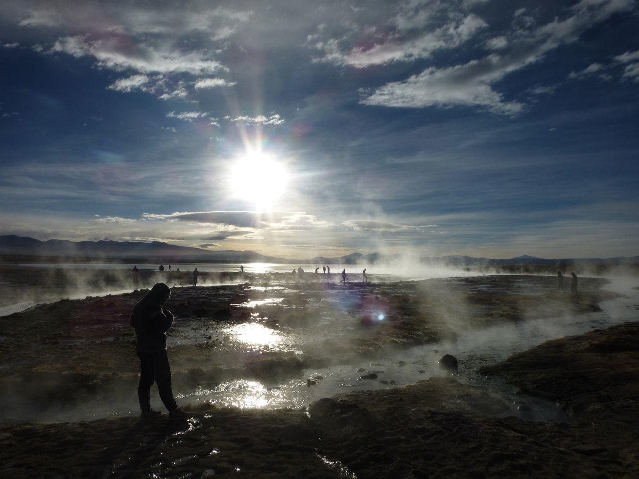 REAR VIEW OF WOMAN STANDING ON BEACH AGAINST SKY