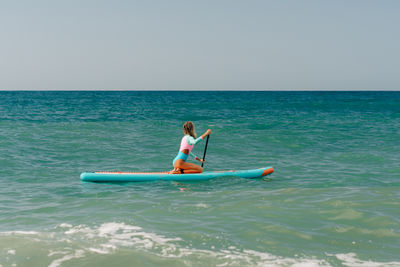 Man kayaking on sea against clear sky