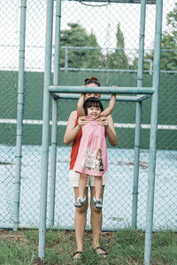 Portrait of smiling girl standing against fence