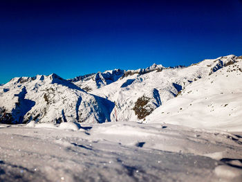 Scenic view of snowcapped mountains against clear blue sky