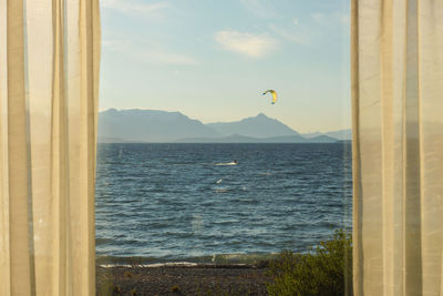 Scenic view of sea against sky with kite surfer passing through 