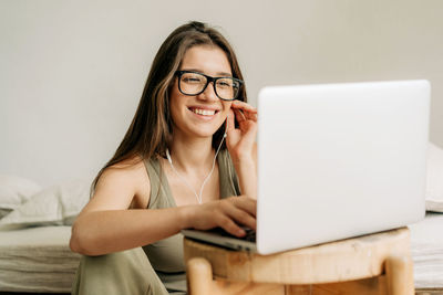 Portrait of young woman using mobile phone while sitting on table