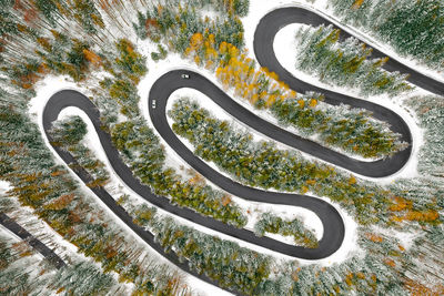 Aerial view of cars on winding road in winter forest