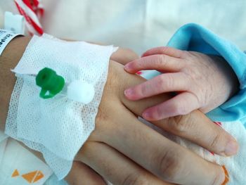 Close-up of medical equipment on woman by baby hand at hospital