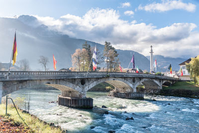 Arch bridge over river against cloudy sky