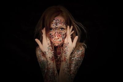Close-up of young woman against black background