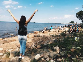 Woman standing at beach against sky