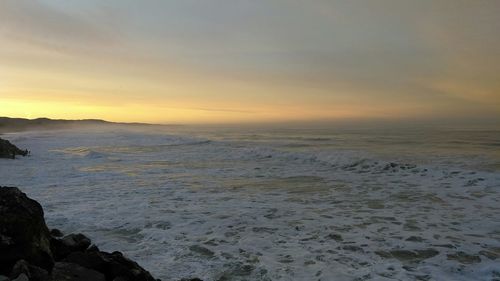 Scenic view of sea against dramatic sky during sunset