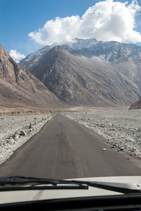 Road amidst mountains seen through car windshield