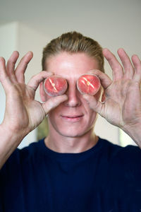 Portrait of man holding peaches over eyes