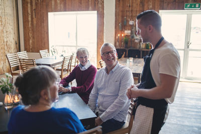 Young waiter taking order from senior people in restaurant