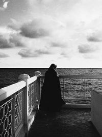 Rear view of woman on railing against sky