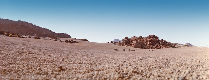 Scenic view of desert land against clear blue sky