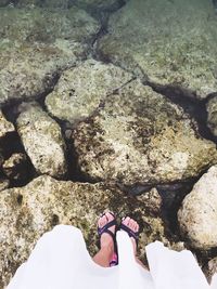 Low section of woman standing on rock by sea