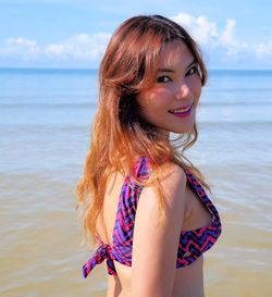 Portrait of smiling young woman standing on beach