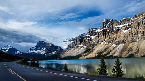 Road by snowcapped mountains against sky