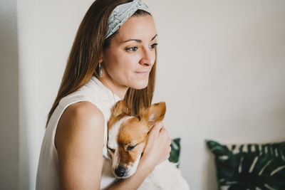 Close-up of woman with dog sitting a home