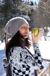 Close-up of smiling mature woman holding fruit during winter