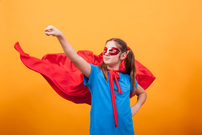 Portrait of young woman wearing sunglasses against yellow background