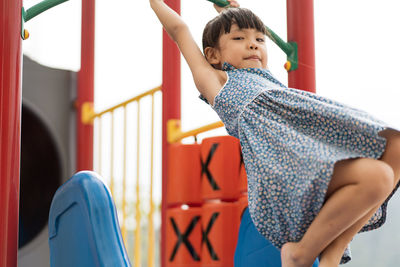 Full length of happy girl playing on jungle gym at park