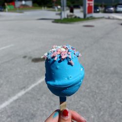 Close-up of hand holding ice cream on road