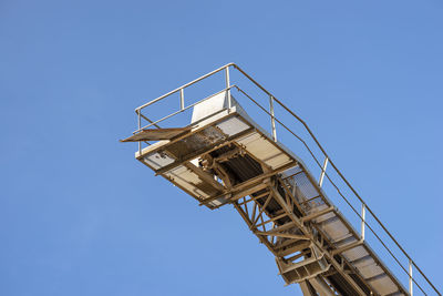 Conveyor belt for gravel against the blue sky at an industrial cement plant.