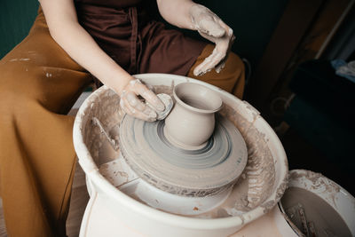 Midsection of woman making pottery at workshop