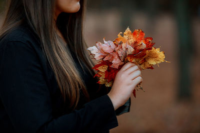 Midsection of woman holding flowering plant