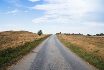 Road amidst field against sky