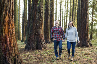 Attractive couple walking through forest, looking ahead.