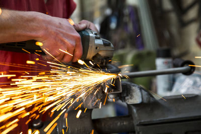 Midsection of worker using circular saw at workshop