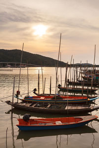 Boats moored in sea against sky during sunset