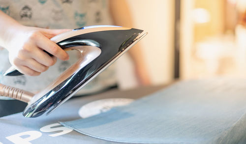 Female hand ironing clothes on iron board at home in the laundry day.