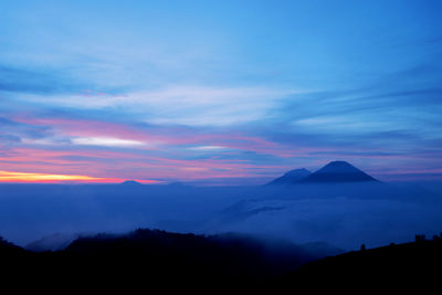 Silhouette of mountain range against cloudy sky