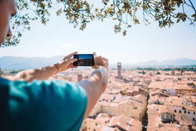 Man photographing with mobile phone against sky