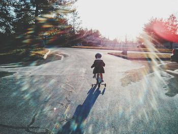 Child riding bicycle on road against clear sky