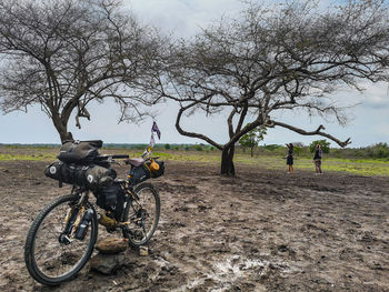 People riding bicycle on field against sky