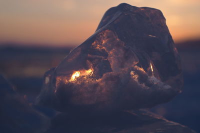 Close-up of campfire on rock against sky during sunset