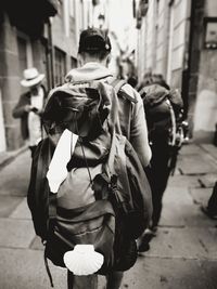 Rear view of man wearing backpack while walking on footpath