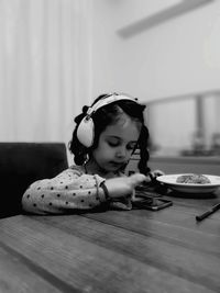 Cute girl listening music while having breakfast at home