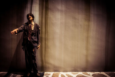 Young man looking away while standing against wall