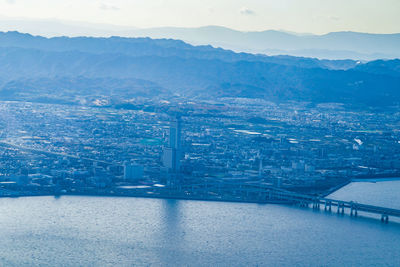 High angle view of city by sea against sky