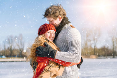 Smiling girl with boyfriend standing outdoors during winter