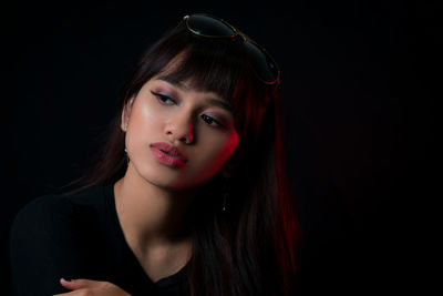 Close-up of young woman against black background